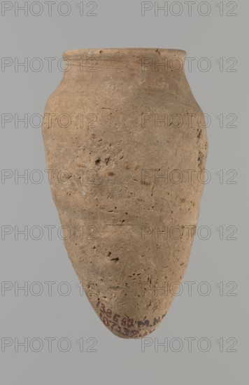 Vessel with hieratic inscription, Egyptian pottery, ceramic conical vessel tapering towards the bottom, irregular, widest at approx. 3/4 of the height. Narrow, slightly sloping shoulders; short, wide neck; very gently rounded, slightly flaring rim; pointed bottom. Handcrafted; upper part shoulders, neck, rim turned. Smooth surface, externally probably covered with a layer of engobe. Made of Nile clay NB2 Vienna System. Remains of a hieratic inscription in black on lower part of the belly. Well preserved with slight damage to the rim. Analogies: Petrie, Dendera, Hope, Akhmim, Reisner, Brunton, Mace, Keiser et al.; earlier dated to the 4th–5th Dynasty; ca. 2686–ca. 2181 BC; Old Kingdom, Edfu. Dimensions: height 13.9 cm; lip diameter 5.9 cm; max diameter 8 cm., A single earthenware jar with a rounded body tapering to a pointed base, shown against a plain gray background. The vessel's surface is rough and pitted with visible irregularities and small indentations. The rim is slightly flared...