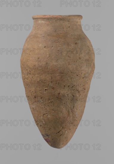 Vessel with hieratic inscription, Egyptian pottery vessel of clay, Old Kingdom, ca. 2686–2181 BC, Edfu findspot. Comparative parallels: Petrie, Dendera, pl. XVI.2; Hope, Akhmim, fig. 7, type AIVa 2bi; Reisner, Mycerinus, p. 212, fig. 64 3,4; Brunton, Qau and Badari, pl. LXXXI type 77N; Mace, Naga ed-Der II, figs. 87.11–14, 16–25; Reisner, Naga ed-Der III, fig. 28–33; Petrie, Abydos II, pl. XLIII, 79–80; Keiser, Avila, Dreyer, Jaritz, Laskowaska-Kusztal, MDAIK 40, fig. 9b. Dimensions: height 15.1 cm; rim diameter 5.6 cm; body diameter 8.2 cm., A single large pottery vessel with a rounded body tapering to a pointed base is shown against a plain background, its surface rough and pitted with visible texture and small indentations; the neck flares slightly to a thick rim and the vessel displays an overall earthy brown color with patches of lighter beige and subtle darker brown variations, as well as a few small areas of muted mottled gray and faint traces of reddish and purple tones near th...