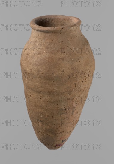 Vessel with hieratic inscription, Egyptian pottery vessel ceramic, clay, Old Kingdom, ca. 2686–ca. 2181 BC; comparative parallels: Petrie, Dendera, pl. XVI,2; Hope, Akhmim, fig. 7 type AIVa 2bi; Reisner, Mycerinus, p. 212, fig. 64 3,4; Brunton, Qau and Badari, pl. LXXXI type 77N — earlier dated to the IV–Vth Dynasty; Mace, Naga ed-Der II, figs. 87.11–14, 16–25; Reisner, Naga ed-Der III, fig. 28–33; Petrie, Abydos II, pl. XLIII, 79–80; Keiser, Avila, Dreyer, Jaritz, Laskowska-Kusztal, MDAIK 40, fig. 9b. Find site: Edfu. Vessel dimensions: height 15.1 cm; rim dia. 5.6 cm; body dia. 8.2 cm., A single tall, rounded clay vessel with a narrow neck and flared rim rests against a plain background; the surface of the vessel shows a rough, textured finish with small pits and irregularities, and its overall color is various shades of brown with hints of darker and lighter brown mottling and small flecks of beige and gray.