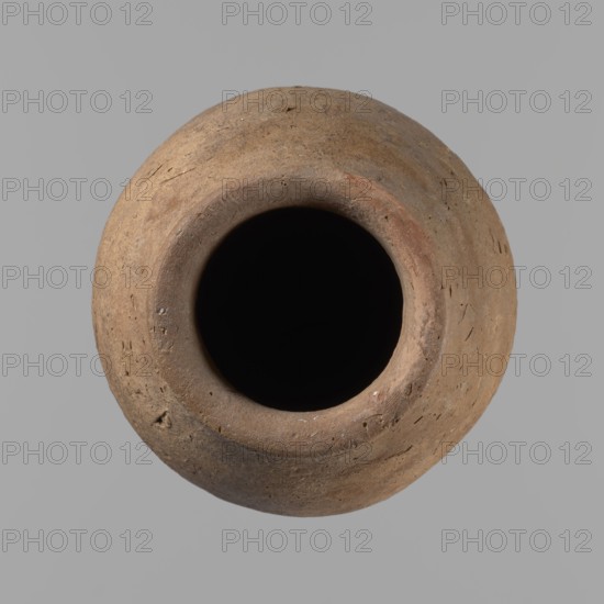 Vessel with hieratic inscription, Egyptian pottery ceramic clay vessel, Old Kingdom, ca. 2686–2181 BC, excavated at Edfu; vessel height 15.1 cm, rim diameter 5.6 cm, body diameter 8.2 cm. Comparative material: Petrie, Dendera pl. XVI.2; Hope, Akhmim fig. 7 type AIVa 2bi; Reisner, Mycerinus p. 212 fig. 64 3,4; Brunton, Qau and Badari pl. LXXXI type 77N; Mace, Naga ed-Der II figs. 87.11–14, 16–25; Reisner, Naga ed-Der III fig. 28–33; Petrie, Abydos II pl. XLIII 79–80; Keiser, Avila, Dreyer, Jaritz, Laskowaska-Kusztal, MDAIK 40 fig. 9b., A round clay vessel viewed from above with a wide central opening and a thick rounded rim, showing a rough textured surface with small pits and irregularities; the vessel is mostly earthy brown with patches of lighter tan and subtle reddish-brown tones, and the interior appears very dark to black, all set against a flat light gray background.