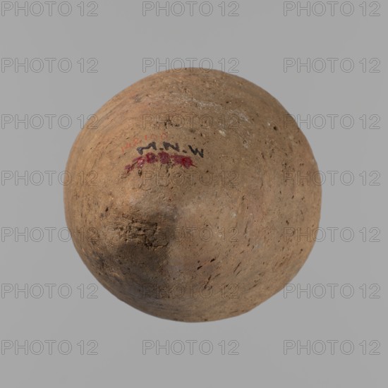 Vessel with hieratic inscription, Egyptian pottery vessel in clay, Old Kingdom ca. 2686–ca. 2181 BC, Edfu findsite. Comparative materials: Petrie, Dendera, pl. XVI,2; Hope, Akhmim, fig. 7, type AIVa 2bi; Reisner, Mycerinus, p. 212, fig. 64 3,4; Brunton, Qau and Badari, pl. LXXXI type 77N — earlier dated to the IVth–Vth Dynasty; Mace, Naga ed-Der II, figs. 87.11–14, 16–25; Reisner, Naga ed-Der III, fig. 28–33; Petrie, Abydos II, pl. XLIII, 79–80; Keiser, Avila, Dreyer, Jaritz, Laskowaska-Kusztal, MDAIK 40, fig. 9b. Dimensions: height 15.1 cm; rim diameter 5.6 cm; body diameter 8.2 cm., A roughly spherical object with a textured, uneven surface in shades of brown and tan, showing small pits and rough patches; a small area of dark red and dark markings is visible on one side; the background is a smooth light gray.