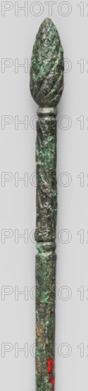 Hairpin with a head in the form of a pine cone; maker: Semerau-Siemianowski, Wladyslaw 1849–1938; pine cones; women's accessory; 5th–4th century BC; Etruria; decoration; weight 6 g; height 14.2 cm; diameter 0.4 cm, A long slender metallic object with a textured surface, topped by a pointed, pinecone-like finial; the metal shows a rough, corroded patina with shades of green and darker grayish-brown, with small areas of reddish discoloration near the lower portion; the object is displayed vertically against a light neutral background.