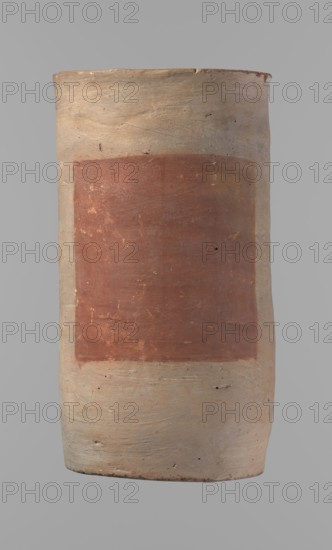 Canopic urn. Clay canopic urn with a cylindrical shape and a flat bottom; flat, straight rim. Vessel made on the wheel of Nile clay type NB2 Vienna System. Bottom cut off with a knife; surface leveled. On the outer wall is a rectangle painted in red, 11.5 cm wide by 11 cm high. Color light brown. Preservation quite good; rim partially filled with plaster and painted. ca. 1550–ca. 1069 BC New Kingdom, Deir el-Medina. Vessel; height 23.5 cm, rim diameter 12.5 cm, bottom diameter 11.4 cm., A cylindrical clay vessel shown upright against a neutral background, with a wide rectangular reddish-brown painted panel on its front; the vessel's body is a pale beige-cream color with visible brush and clay texture, small dark specks and tiny pits in the surface, and subtle horizontal striations; the rim is slightly uneven and darker beige with a few small chips, and the base area shows some darker smudges and soil-colored marks.