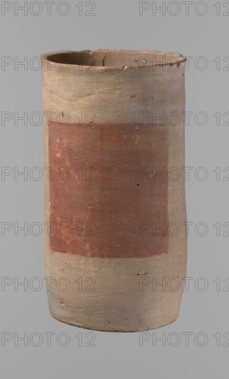 Canopic urn, Clay canopic urn with a cylindrical shape and a flat bottom and flat, straight rim. Made on the wheel of Nile clay type NB2 Vienna System. Bottom cut off with a knife; surface leveled. Outer wall painted with a red rectangle measuring 11.5 cm × 11 cm. Color light brown. Rim partially filled with plaster and painted. Date: ca. 1550–ca. 1069 BC New Kingdom, provenance: Deir el-Medina. Vessel; height 23.5 cm, rim diameter 12.5 cm, bottom diameter 11.4 cm., A tall cylindrical clay vessel with an uneven rim and a slightly tapered base, showing a large rectangular painted area on its side; the vessel's surface is rough with visible tool marks, small chips, and pitting. The visible colors are muted beige and light tan across most of the vessel, a broad rusty red rectangular panel on the body, and small darker brown spots and scratches. The background is a uniform neutral gray.