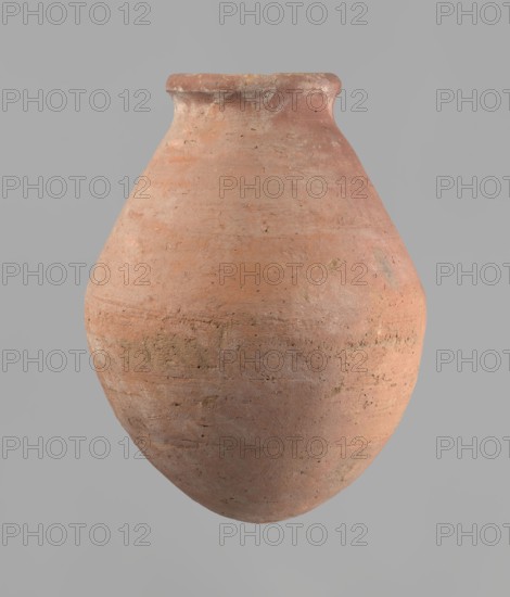 Vessel, Egyptian ceramics. Wheel-made from Nile clay of type NB2 Vienna System. Ovoid belly, wide short neck, rounded bottom, straight upturned rim. Surface levelled and covered with engobe; outer surface red, inner surface yellowish-brown. Firing hole at widest circumference, approx. 1 cm diameter. Well-preserved. ca. 1550–1295 BC; New Kingdom, 18th Dynasty; Deir el-Medina. Vessel: height 27 cm; rim diameter 11 cm; body diameter 20.5 cm., A large rounded clay vessel with a narrow neck and slightly flared rim is centered against a plain light gray background; the surface of the vessel shows a rough, textured finish with visible small pits and irregularities and a gradient of earthy colors including terracotta, muted orange, pale pink, and areas of dusty brown and gray, with subtle darker speckles and weathered patches.
