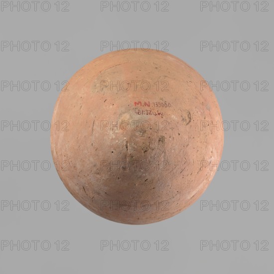 Vessel with an ovoid belly, a wide short neck and a rounded bottom. Straight, upturned rim. Wheel-made from Nile clay of type NB2 Vienna System. Surface levelled and outer surface covered with engobe. Outer surface red; inner surface yellowish-brown. Firing hole at the widest circumference, approx. 1 cm diameter. Well-preserved. ca. 1550–1295 BC; New Kingdom, 18th Dynasty; from Deir el-Medina. Vessel; height 27 cm, rim diameter 11 cm, body diameter 20.5 cm., A rounded, bowl-like object with a textured, worn surface in shades of terracotta and light brown sits against a flat gray background; the object shows areas of darker brown patches and small dark speckles, subtle circular marks and scratches, and a few smudged, slightly reddish areas.