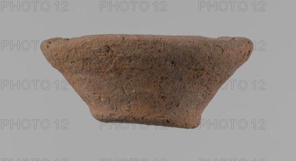 Bowl, probably votive, conical shape with flat bottom. Irregular walls; straight, slightly flaring rim; irregular bottom, probably cut off with a string. Wheel-made vessel of Nile clay type NC Vienna System. Surface only slightly leveled. Vessel color: brown. Well-preserved with only minor surface erosion. c. 1550–c. 1069 BC, New Kingdom, Deir el-Medina. Ceramic bowl, height 3.7 cm; diameter 8.2 cm lip, 4.2 cm bottom., A roughly conical, textured object with an irregular, worn surface fills the center of the image, showing a coarse, grainy texture and pitted areas; the object displays shades of brown and reddish-brown with small darker and lighter speckles, set against a uniform light gray background.