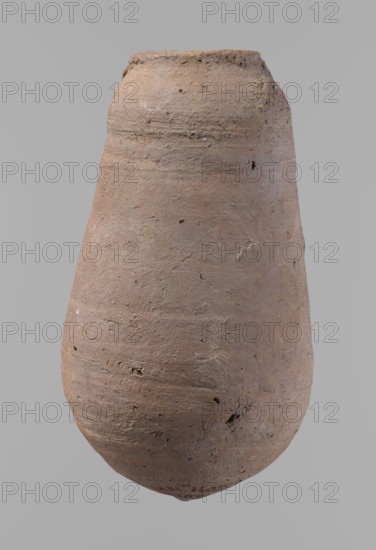 Vessel, unknown creator; Egyptian pottery, ceramic clay vessel; New Kingdom ; from Deir el-Medina, height 18.5 cm, rim diameter 5.2 cm, body diameter 10.2 cm., A roughly pear-shaped ceramic vessel with a textured surface showing irregularities and small pits, primarily in shades of earthy brown and tan with subtle areas of darker brown and faint gray; the vessel has a narrow flat rim at the top and a rounded, slightly bulbous body tapering toward the bottom, with visible horizontal tool marks and uneven surface roughness.