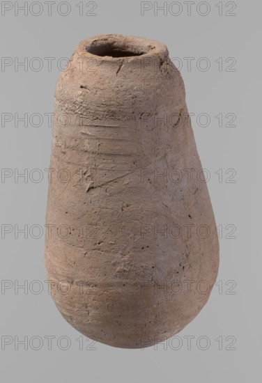 Vessel, Egyptian pottery ceramic clay vessel; New Kingdom, from Deir el-Medina; vessel; height 18.5 cm, rim diameter 5.2 cm, body diameter 10.2 cm., A single large rounded vessel with a narrow open mouth and an uneven rim, showing a rough, textured surface with visible tool marks and small pits; the vessel appears handmade with an irregular, slightly asymmetrical profile and subtle surface striations and scratches; color tones visible include shades of brown, beige, tan, and hints of earthy orange against a plain gray background.