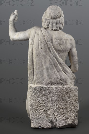 Statue of Jupiter of the Capitoline type, unknown Roman workshop, Scen.Gal.Class., deposit, Collection of Ancient Art, Jupiter mythology, Zeus mythology, Roman sculpture, Roman copy after a Hellenistic variant of Phidias's statue of Zeus the Olympian. Zeus seated on a throne set on a rectangular base. Zeus sits stiffly with his torso slightly back. His raised left hand holds a scepter. His right hand rests on his right knee. The right foot is slightly forward. The legs are covered with a himation, which also covers the back and left shoulder. The muscular torso, strongly developed at the shoulders, has naturalistic modeling. The head is disproportionately large, and the face is perfect with a slightly open mouth. The hair is parted from the center anastole. The beard is thick, arranged in strands on the sides and in curls on the chin. Late 2nd–3rd century, Roman Empire 27 BC–476 AD, sculpture, weight 930 kg, A rear view of a stone sculpture depicting a seated male figure with wavy hair...