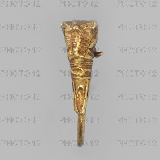 Earring decorated with a bull's head; classified Gallic scenography, bucranium ornament; pendants; goldsmithery; 3rd century BC; Greece; jewelry; height 1.5 cm, width 1.1 cm, depth 0.4 cm, weight 1 g;, A small metallic object with a worn gold surface is shown against a plain light gray background; the object has a tapered vertical shape with a broader textured top that narrows into a ridged midsection and a slimmer lower portion ending in a curved loop, and the gold color shows areas of slightly darker and lighter patina.