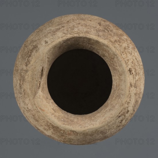 Globular vessel, unknown Northern Mesopotamian workshop, clay, Early Jazira III period ca. 2600–ca. 2350 BC / Early Dynastic III period, globular vessel with a low conically flaring neck terminating in a narrow, slightly thickened and everted rim, rounded slightly flattened bottom, height 8.4 cm, width 9.5 cm; provenance: Tell Rad Shakra, Khabur basin, Northern Mesopotamia Al-Jazira, Syria., A round, textured object with earthy beige and light brown tones viewed from above, showing a wide dark central opening and a raised rim with a rough surface; the surrounding background is a solid muted gray.