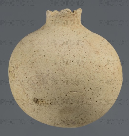 Globular vessel, unknown Northern Mesopotamian workshop; Early Jazira III period ca. 2600–ca. 2350 BC / Early Dynastic III; globular vessel with a narrow neck upper part of the neck and spout not preserved; thickened circular base; clay vessel for oils and ointments; vice-free vessel; Al-Jazira Northern Mesopotamia, Khabur basin; Tell Rad Shakra, Syria site of discovery; height 11.3 cm, width 10.45 cm., A rounded, bulbous object with a narrow, irregular opening at the top sits against a plain background; the object has a rough, pitted surface with visible small pits and fine cracks, an overall sandy beige color with areas of darker tan and subtle brown speckling, and a slightly uneven rim that appears chipped in places.