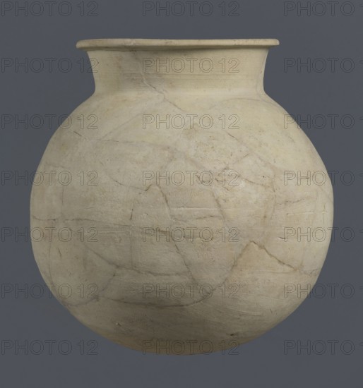 Globular vessel, unknown Northern Mesopotamian workshop; globular vessel, clay; excavations of the Centre of Mediterranean Archaeology, University of Warsaw removed; Early Jazira III period ca. 2600–ca. 2350 BC; vice-less vessels; children's graves; Al-Jazira Syria; Iraq; Mesopotamia; Early Dynastic III period ca. 2600–ca. 2350 BC; Northern Mesopotamia Khabur basin; Tell Rad Shakra northeastern Syria; Globular vessel with a distinct, slightly flared conical neck ending with an outwardly extended and everted rounded rim; ca. 2600–ca. 2350 BC; vessel; height 19 cm; width 18.2 cm., A large rounded clay vessel sits against a solid dark gray background, showing a pale beige surface with subtle variations of off-white and light tan; the pot has a short flared neck and a wide body with visible repair lines and hairline cracks that form irregular curved patterns across its surface, along with faint textured tool marks and slightly darker smudges and spots in places.