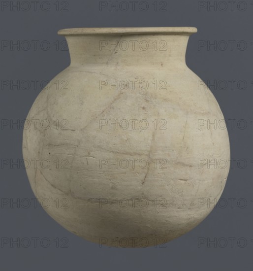 Globular vessel, unknown Northern Mesopotamian workshop; globular vessel; clay; Early Jazira III period ca. 2600–ca. 2350 BC / Early Dynastic III period ca. 2600–ca. 2350 BC; vice-less vessels; used in children's graves; Al-Jazira Syria/Iraq, Mesopotamia; Northern Mesopotamia Khabur basin; Tell Rad Shakra northeastern Syria; Globular vessel with a distinct, slightly flared conical neck ending in an outwardly extended and everted rounded rim; height 19 cm, width 18.2 cm., A round ceramic vessel with a wide neck and flared rim suspended against a solid background; the vessel surface is matte and shows uneven texture with visible cracks and repairs, exhibiting shades of off-white, cream, beige, and faint pale gray, while the background is a uniform dark gray.