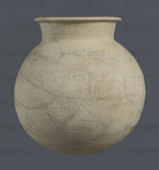 Globular vessel, unknown Northern Mesopotamian workshop, globular vessel, clay, excavations of the Centre of Mediterranean Archaeology, University of Warsaw, Early Jazira III period ca. 2600–ca. 2350 BC, vice-less vessel, children's grave context, Al-Jazira Syria; Iraq; Mesopotamia, Early Dynastic III period ca. 2600–ca. 2350 BC. Globular vessel with a distinct, slightly flared conical neck ending in an outwardly extended and everted rounded rim. ca. 2600–ca. 2350 BC; Syria, Northern Mesopotamia Khabur basin, Tell Rad Shakra northeastern Syria. Vessel; height 19 cm; width 18.2 cm., A large rounded clay vessel with a narrow neck and flared rim fills the frame, showing a worn, matte surface with visible patched repairs and fine cracks. The vessel displays a range of pale beige, off-white, cream, and light tan tones with subtle areas of darker grayish-beige and faint rusty discoloration. The texture appears rough and slightly porous in places, with irregular lines and seams where fragment...