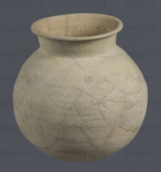 Globular vessel, unknown Northern Mesopotamian workshop; globular vessels; clay vessel from Early Jazira III period ca. 2600–ca. 2350 BC / Early Dynastic III period ca. 2600–ca. 2350 BC; associated with vice-less vessels and children's graves; Al-Jazira Syria/Iraq, Mesopotamia; Northern Mesopotamia Khabur basin; Tell Rad Shakra northeastern Syria; Globular vessel with a distinct, slightly flared conical neck ending with an outwardly extended and everted rounded rim; ca. 2600–ca. 2350 BC; height 19 cm, width 18.2 cm., A round, bulbous ceramic vessel with a wide flared rim, shown against a solid gray background; the vessel surface is matte and pale beige to off-white with subtle variations in tone and a few areas of light brown discoloration, visible hairline cracks and repair lines forming irregular patchwork across the body, and a slightly rough, textured finish inside and out.