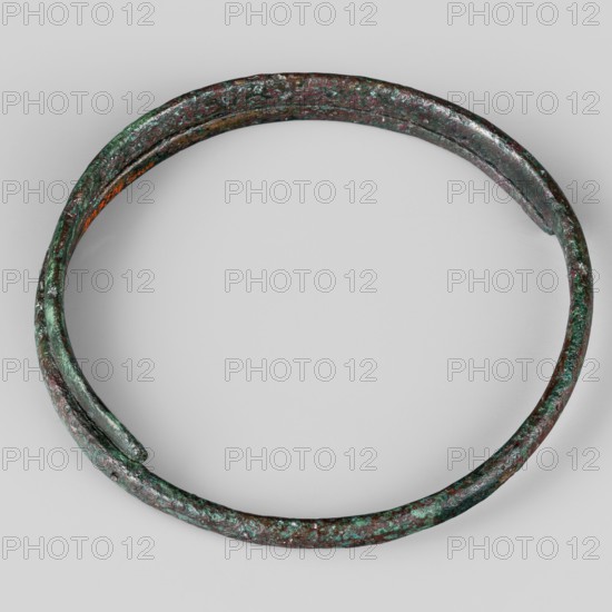 Bracelet, Made of flattened wire with thinning, overlapping ends. 9th–8th century BC; Villanovian period, Etruria. Body ornament; weight 46 g; height 1.2 cm; diameter 8.5 cm., A circular metal ring with a rough, pitted surface shown against a light gray background, the ring displaying a mottled mix of green and brown tones with areas of darker brown and hints of turquoise and rust-colored spots, the band appearing slightly irregular in shape with one end overlapping the other and textured unevenly along its length.
