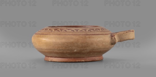 Exaleiptron kothon on a low, conical foot; ribbon-shaped base; upper part and inner surface covered with red varnish thin, uneven layer; outer part of foot covered with red varnish. Band decoration painted on clay with delicate orange/red lines and concentric circles on the bottom. Main decorative ornament consists of smaller, narrower leaves; plant and geometric motifs. Smooth surface with visible traces of turning; fine-grained clay with visible pyroxene. Glued artifact with visible conservation work; large losses in varnish and impurities inside. Clay color: 10 R 5/4 weak red, 10 R 5/8 red. Attributed to Corinth; 2nd half of the 6th century BC. Vessel kothon, exaleiptron. Height 5.5 cm, width 17.4 cm, depth 14.5 cm, weight 0.304 kg., A shallow, rounded ceramic bowl with a short spout on one side resting on a low circular foot; the bowl is primarily tan and light brown with darker reddish-brown painted bands and a decorative band of small abstract shapes near the rim, the spout showi...