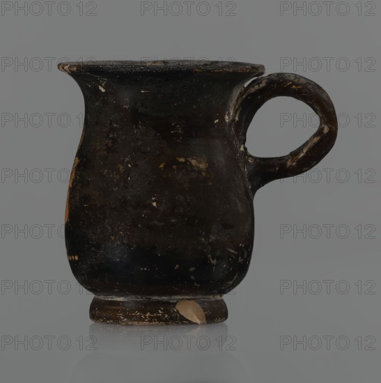 Jug, red-figure pottery, Greek pottery, mermaid mythological, Athens Greece. A small jug with a low foot recessed at the bottom. The edges of the foot are slightly rounded and tapered upwards. The body is slightly wider than the foot, rounded at the bottom, almost cylindrical in the lower half, and gently tapering in the upper half, merging into a widely flared outward spout. Below the spout is a vertically mounted, cylindrical, slightly flattened handle, bent into a circle. Light orange clay, black shiny firnis. On the body, the mermaid is in right profile, with wings raised upwards the left wing at the back, protruding above the right. On the mermaid's head is a diadem marked with white dots. Feathers marked with lines—long and thin at the wingtips and tail; thin and thick elsewhere. The image is emphasized from the bottom with a row of dots. The side of the foot is chipped, the rim edge is slightly chipped, and the firnis is abrasion-stripped. Part of the rim is filled with plaster....
