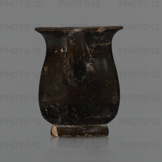 Jug, red-figure pottery, Greek pottery, mermaid mythological, Athens Greece. A small jug with a low foot recessed at the bottom. The edges of the foot are slightly rounded and tapered upwards. The body is slightly wider than the foot, rounded at the bottom, almost cylindrical in the lower half, and gently tapering in the upper half, merging into a widely flared outward spout. Below the spout is a vertically mounted, cylindrical, slightly flattened handle, bent into a circle. Light orange clay, black, shiny firnis. On the body the mermaid is in right profile with wings raised upwards the left wing at the back, protruding above the right. On the mermaid's head is a diadem marked with white dots. Feathers marked with lines—long and thin at the wingtips and tail; thin and thick elsewhere. The image is emphasized from the bottom with a row of dots. The side of the foot is chipped, the rim edge is slightly chipped, and the firnis shows abrasion. Part of the rim is filled with plaster. 3rd qu...
