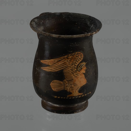 Jug, red-figure pottery, Greek pottery, mermaid mythological, Athens Greece. A small jug with a low foot recessed at the bottom. The edges of the foot are slightly rounded and tapered upwards. The body is slightly wider than the foot, rounded at the bottom, almost cylindrical in the lower half, and gently tapering in the upper half, merging into a widely flared outward spout. Below the spout is a vertically mounted, cylindrical, slightly flattened handle, bent into a circle. Light orange clay, black, shiny firnis. On the body, the mermaid is in right profile, with wings raised upwards the left wing at the back, protruding above the right. On the mermaid's head is a diadem marked with white dots. Feathers marked with lines—long and thin at the wingtips and tail; thin and thick elsewhere. The image is emphasized from the bottom with a row of dots. The side of the foot is chipped, the rim edge is slightly chipped, and the firnis is abrasion-stripped. Part of the rim is filled with plaster...