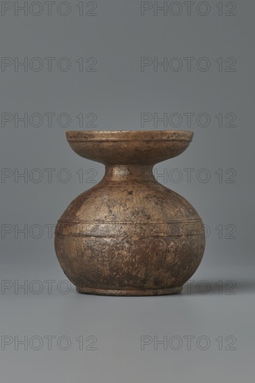 Aryballos, 2nd–1st century BC, Sicily Segesta - incorrect information?, Etruria, vessel aryballos, weight 0.11 kg, height 5.4 cm, diameter 5 cm, A round, bulbous vessel with a narrow neck and a wide, shallow rim sits centered against a plain background; the object has a rough, textured surface with visible wear and irregularities and shows a mix of brown, bronze, and muted gold tones with darker brown patches, while the backdrop and surface beneath the vessel are shades of gray.