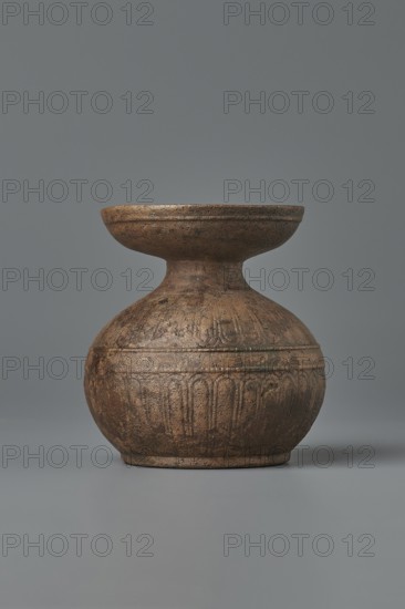 Aryballos, 2nd–1st century BC, Sicily Segesta - incorrect information?, Etruria, vessel aryballos, weight 0.11 kg, height 5.4 cm, diameter 5 cm, A single round vessel with a wide, shallow rim sits centered against a plain gray background; the object is made of a textured material in various shades of brown with darker brown and subtle black speckling, showing a bulbous lower body, a narrow neck, and a flaring upper dish, and the lower section displays carved or impressed vertical arch-like patterns while the surface shows irregular marks and a slightly matte finish.