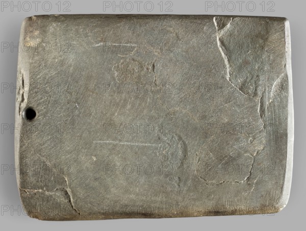 Rectangular paddle with a hole at one of the shorter edges; possibly a whetstone. Flat rectangular paddle, geometric design; paddle, height 8.2 cm, width 11.1 cm, weight 0.174 kg. Dated to the 2nd half of the 4th millennium BC; Predynastic Period Naqada III phase, Egypt., A rectangular stone slab with rounded corners and a matte, slightly rough surface showing a range of gray tones from light to dark, with areas of brownish-gray and subtle greenish-gray; the surface has several irregular cracks and patches where the texture and color shift, plus a few shallow scratches and worn spots; a small round hole is visible near one short edge; the slab rests on a neutral light-gray background.