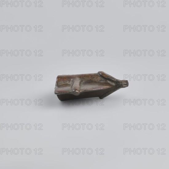Battle axe, Eastern Gallic Scenography, 2nd half of 3rd millennium BC, Western Iran, weapon, weight 280 g, A small sculptural object rests on a smooth pale gray background, showing a worn surface with a mix of brown, dark brown, and subtle greenish patina; the object has an elongated, slightly rectangular base with raised ridges and a tapered end that narrows into a rounded tip, and its surface appears glossy in places with areas of darker shadow and lighter highlights.