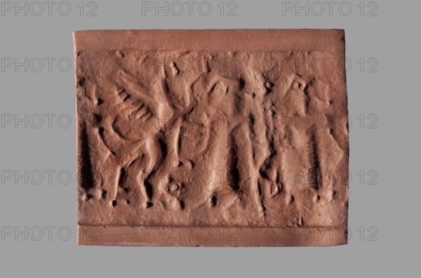 Cylinder seal with a mythological scene, unknown Cypriot workshop. Mythological scene depicting two human figures dressed in long, crosswise pleated robes, standing opposite a winged lion standing on its back. The first figure holds the lowered left front paw of the lion with its outstretched right hand; its left hand is lowered. The second figure, standing behind the first, holds a four-legged animal hanging upside down by its hind legs in its right hand; its left hand is lowered and extended towards the lion's hind legs. The animal is squeezed into a narrow space between the standing figures. Fantasy creatures; winged lions; Eastern Gallic scene. Seal; Cyprus, Near East; Late Bronze Period, 14th century BC previously dated 15th–14th century BC. Height 2.55 cm, width 1 cm., A rectangular reddish-brown clay or terracotta relief with uneven, textured surface and shallow carved impressions suggesting outlines of figures and abstract shapes, set against a plain neutral gray background; th...