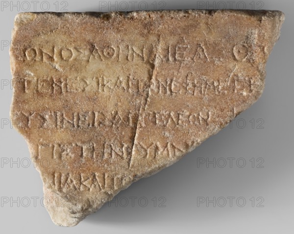 Honorific inscription of Theagenes, son of Theon; unknown creator; Greek inscription on a marble block covered with a pink patina, fragmentarily preserved only the top edge is original. Five lines of Greek text visible. Dated 115–110 BC. Egypt, Pharbaitos place of origin/finding. Inscription Greek. Height 15.2 cm, width 21 cm, depth 8 cm, weight 3.70 kg., A roughly triangular stone fragment with carved grooves and shallow incised lines across its surface, showing a weathered, pitted texture and some rough edges; the stone displays a range of beige, tan, light brown, and pale cream colors with slightly darker brown areas and faint grayish tones, and a thin diagonal crack runs across part of the surface.