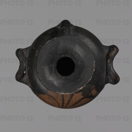Miniature hydria, Miniature hydria with a disc-shaped foot with a profiled edge, an oval body with slightly rounded shoulders, a high neck, and cylindrical handles. The body is decorated with an 11-petal palmette. Reddish clay with black firnis with a matte sheen; black-figure and red-figure pottery characteristics. Antique vessel, hydria, miniature vessel, Southern Italy, Ancient Greece/antiquity, 2nd half of the 4th century BC. Height 11.8 cm, width 7.3 cm., A top-down view of a round ceramic vessel with a wide circular mouth and a dark interior, showing a mostly blackened upper surface with areas of brown and reddish-brown near the lower rim, and a few darker painted linear decorations on the brown area; the vessel has two small looped handles on opposite sides that are dark with patches of worn brown, and the background is a flat gray.