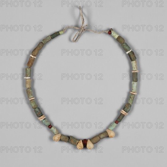 Necklace, salvage excavations, 4th Cataract Sudan, Necklace consisting of 28 cylindrical faience beads with a bluish and greenish glaze, 10 flat disc-shaped ostrich egg beads, 4 red glass beads of a spherical shape and 4 teardrop-shaped white quartz beads, 4th–6th century; Post-Meroitic period, Ashkot 1/T4, jewelry, A necklace made of a twisted light brown cord tied in a simple bow at the top, strung with a series of cylindrical and irregular beads in shades of green and turquoise with visible weathered patina, interspersed with a few small round beads in dark red and several disc-shaped beads in off-white, and a group of teardrop-shaped beads in pale beige near the lower center, all arranged against a uniform light gray background.