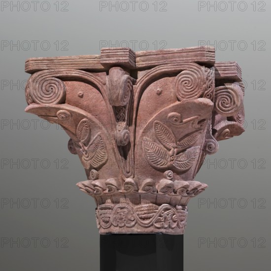 Upper and lower fragments of the capital reconstructed to their complete form. Nubian workshop. Architectural element; capital preserved in two fragments, reconstructed to its complete form. The high neck is decorated with a wavy vine twig with stylized leaves at the bottom and clusters at the top in an alternating arrangement. Above the neck, the shaft is decorated with a wreath of small plastic leaves adorned with small loops of ribbon. The shaft is decorated with large, wide, smooth leaves. On their surface, branches with symmetrically arranged leaves and marked veins are depicted in relief. Between the wide leaves are ribbons arranged in a V-shape, forming volutes at the top. Decorative, plastic elements in an S-shape emerge from between the ribbons, forming supports for the abacus's protrusions. The abacus is low, divided into three layers by two engraved lines. Large capitals of this type were part of the decor of the older basilica and topped the columns of the main nave; pairs ...