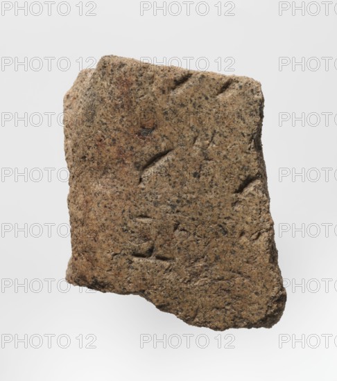 Inscription - fragment, unknown,  craftsman, inscriptions. Granite fragment with engraved hieroglyphic inscription, 760–653 BC; Third Intermediate Period; 25th Dynasty. Old Dongola type of site / place of finding. Inscription, height 8 cm, width 7 cm., A roughly rectangular piece of coarse, grainy stone with irregular, chipped edges and a textured surface showing small pits and indentations, colored mainly light brown with speckles of darker brown and black and a few reddish-brown areas; the stone has shallow, curved grooves and depressions on its face and appears photographed against a plain, light gray background.