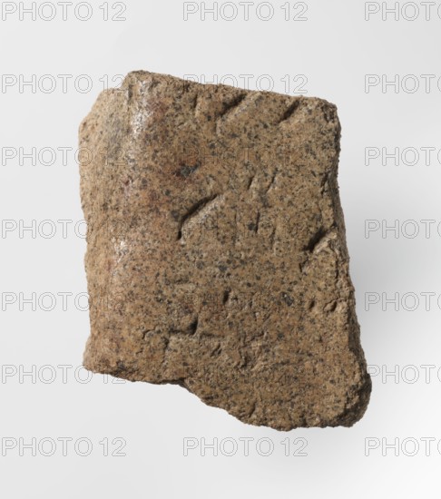 Inscription - fragment, unknown,  craftsman, inscriptions, Granite fragment with engraved hieroglyphic inscription, 760–653 BC; Third Intermediate Period; 25th Dynasty, Old Dongola type of site / place of finding, inscription, height 8 cm, width 7 cm, A roughly rectangular fragment of coarse textured stone with an uneven surface, showing a few shallow grooves and small pits, in colors of tan, brown, gray, and darker speckles, photographed against a plain light gray background.