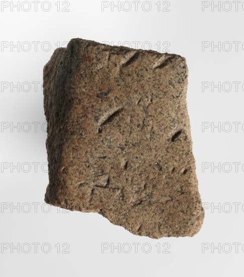 Inscription - fragment, unknown,  craftsman, inscriptions, Granite fragment with engraved hieroglyphic inscription, 760–653 BC; Third Intermediate Period; 25th Dynasty, Old Dongola type of site / place of finding, inscription, height 8 cm, width 7 cm, A roughly rectangular piece of rough-textured stone with irregular edges, showing a grainy surface with pitted indentations and shallow grooves; the stone displays a mix of brown, tan, beige, gray, and darker speckles, with some areas appearing slightly rust-colored and shadowed along one side.