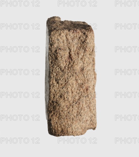 Inscription - fragment, unknown,  craftsman, inscriptions, Granite fragment with engraved hieroglyphic inscription, 760–653 BC; Third Intermediate Period; 25th Dynasty, Old Dongola type of site / place of finding, inscription, height 8 cm, width 7 cm, A roughly rectangular block of coarse, grainy stone shown standing upright against a plain light gray background, with a textured surface composed of a mix of light tan, beige, brown, and hints of darker speckles; the block has uneven, slightly rounded edges and a rugged top with visible pits and small crevices, one narrow vertical face visible from front and one slimmer side face seen in profile, both showing granular surfaces and slight variations in color and roughness.