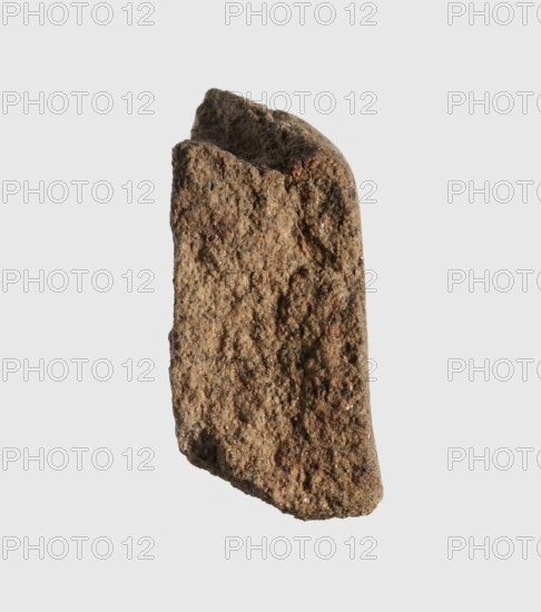 Inscription - fragment, unknown,  craftsman, inscriptions, Granite fragment with engraved hieroglyphic inscription, 760–653 BC; Third Intermediate Period; 25th Dynasty, Old Dongola type of site / place of finding, inscription, height 8 cm, width 7 cm, A single rough-textured fragment with an irregular, elongated shape and uneven edges, showing a coarse granular surface with small pits and bumps; the fragment is mostly brown with shades ranging from light tan to darker brown and scattered darker specks, and it sits against a plain pale gray background.