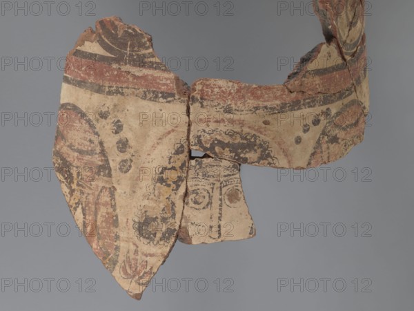Painted storage vessel, fragment of the upper part of a large storage vessel neck and upper body. Decoration painted in black and red on a creamy white underlay. Rim with a thick outward-protruding edge and concave outer surface. Upper part decorated with a row of horizontally running spirals with large red spots, enclosed in red horizontal stripes each bounded by black lines. Below, partially on the body, are figural representations: heads or fragments of male and female figures; the central head is surrounded by a halo. Spaces between heads filled with floral elements in the lower part and black dots in the upper part. Flanking heads wear headgear and have no haloes. Vessel made of Nile clay, medium porous N.B2. 6th century, Egypt. Vessel; external rim diameter 26 cm, height 31 cm., A fragmentary painted ceramic with worn surfaces showing a curved band shape and a partial face motif; the piece displays earthy beige as the base color with visible areas of red, black, brown, and some m...