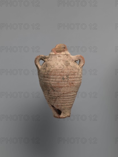 Water vessel qulla, bottle gulla. Ovoid, elongated body, wider in upper part, above half the vessel's height. Low foot, hollow inside, poorly defined externally. Two small vises are glued to the arms, and between them, on an axis perpendicular to their attachment, a conical spout for drinking water is glued. The neck, preserved in its lowest part, is separated from the body by a small, sharply profiled hump. The entire surface of the vessel is covered with light whitewash. Nile clay, medium-porous, 5th century, Tell Atrib, vessel; height 17.0 cm, width 11.5 cm, diameter 4 cm base., An aged clay vessel with a rounded body tapering to a narrow base and a broken tip, featuring a pair of loop handles near the shoulder and horizontal ridged bands around the lower half; the surface shows rough texture, chips, and cracks with areas of wear. The visible colors are muted beige, terracotta, pale brown, and some darker grayish spots against a neutral gray background.