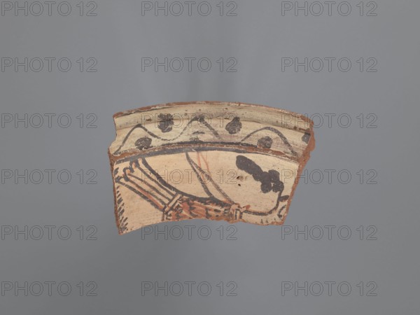 Plate fragment, unknown northern Egyptian workshop, plate with horizontally formed rim. Red-orange ceramic with visible inclusions of gold mica and white-yellow limestone particles. Covered with a white engobe, fired beige with pink in places. Painted black decoration with red elements inside the vessel, consisting of: a circumferential band bounded by parallel lines upper one extending beyond the edge, filled with a wavy line and two rows of dots above and below; a representation of a bird preserving the back, tail, one raised wing, and rear part of the head—wing outlined irregularly in red with irregular filling along the back, plumage/coloration emphasized with lines and motifs horizontal on the neck, three concentric lines around the neck, lines on the back, tail elongated with four long feathers; bunches of grapes, depicted as seven touching dots above the back of the bird’s head; a vertical branch behind the tail, probably separating it from an adjacent image. 6th–7th century. Te...