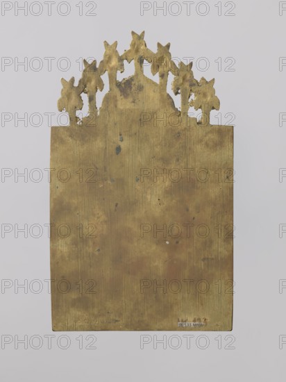 Icon: Holy Fathers of the Church; Old Believers workshop. Metal icon showing Saints Gregory the Theologian, Basil the Great, and John Chrysostom in full-figure, frontal views. They are dressed in bishops' robes, holding books, standing on flower-covered ground. Identifying inscriptions above them. Background horizontally engraved with thin lines. Ribbon ornament surrounding the scene, covered with raised dots. On the icon's axis a medallion topped with a kokoshnik-shaped arch depicts Christ as the High Priest, blessing with both hands. Cherubim and ripidions form a semicircular arch around him. Relief is precise and meticulous, with ornamentation and attention to detail. 19th century, Russia. Dimensions: height 19.8 cm, width 12 cm, depth 0.2 cm., A flat rectangular metal plate with an ornate cutout top showing a row of stylized floral or leaf shapes, the surface showing uneven patina and small dark spots and scratches; colors visible include shades of gold, brass, brown, and a few dar...