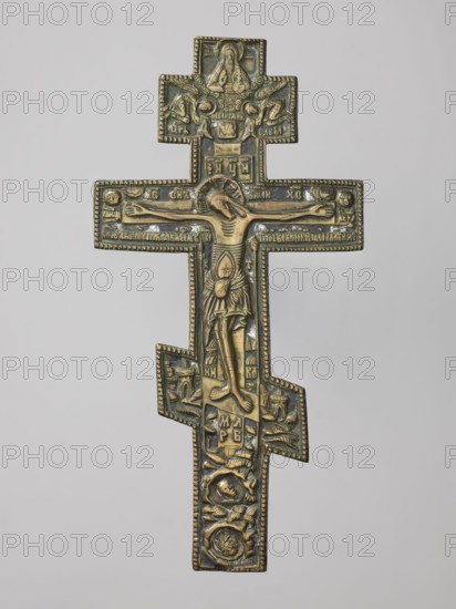 Cross: Crucifixion of Christ, Old Believers workshop; crosses; Lord of Hosts iconography; Jesus Christ Bible; God the Father iconography; sun iconography; Crucifixion iconography; moon iconography; Golgotha iconography; Adam Bible; instruments of the Passion of the Lord iconography; skull iconography; Jerusalem Israel/Palestine; Holy Spirit iconography; Old Believers; inscriptions; halo iconography. On the eight-pointed cross is an image of the Crucifixion. Below the cross on which Christ is suspended is a grotto with Adam's skull and the tree of Seth; at the level of the footstool is a view of Jerusalem; on two sides of Christ on a long beam are the sun and the moon. In the upper part, a bust-like image of the Lord of Hosts is depicted, below which is the dove of the Holy Spirit. The relief is deep in cast, and the style is rather schematic, somewhat archaizing especially visible in the facial features. The background features navy blue and white enamel. The reverse is engraved with t...