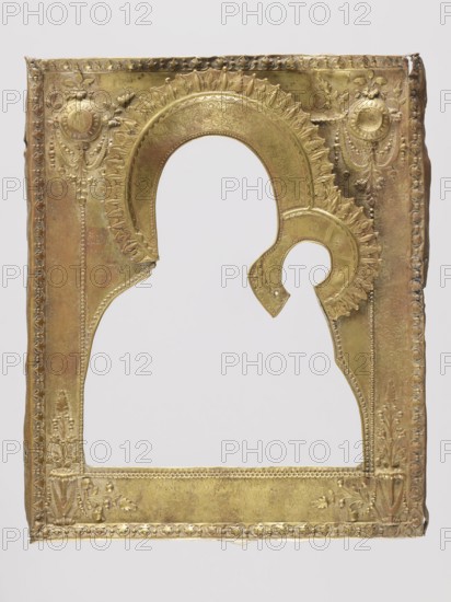 Icon in a cover: Our Lady of Tikhvin, Russian workshop, I.Ch., Mary mother of Jesus Christ, Our Lady of Tikhvin iconography, icons, Jesus Christ Bible, icon covers, Our Lady and Child iconography, maphorion iconography, scrolls, ornaments. Canonical variant of the image of Our Lady of Tikhvin — with colors predominating in green, vermilion, and ochre. The icon was most likely heavily repainted in the 2nd half of the 20th century. It has a cover consisting of a basma, background, and wreaths — brass repoussé, with very rich ornamentation, especially in the corners motif of candelabra, medallions with garlands. The frame is covered with an engraved floral and plant pattern; similarly, the applied haloes are surrounded by radially arranged leaves. 19th century, Russia. Height 31.3 cm; width 24.2 cm., A rectangular metal frame with ornate embossed decoration in gold and brass tones, featuring a large arched cutout and a smaller circular cutout attached to the arch; the surface shows floral...