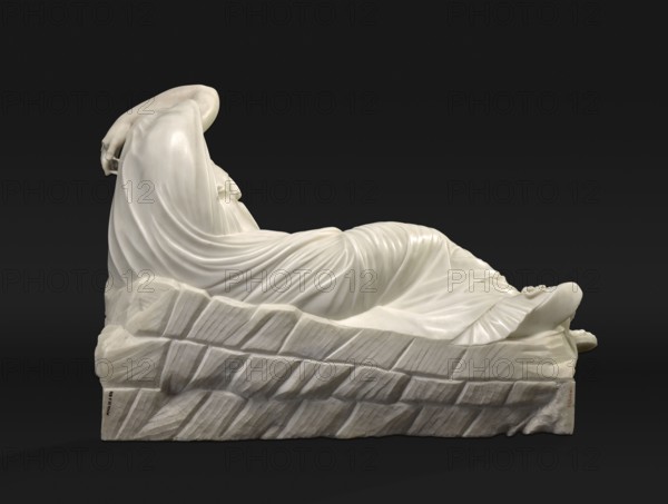 Sleeping Ariadne, Classicist copy of the Hellenistic Sleeping Ariadne original c. 200 BC. It depicts a semi-reclining woman supported by her left arm; the right leg, bent at the knee, obscures the tucked-in left one. The right arm is unnaturally bent above the head. The face is elongated with closed eyes. A long, folded, decoratively wrinkled robe covers the entire body. A bracelet in the form of a snake entwines the left arm, leading to past identifications as an antique representation of the dying Cleopatra. 18th/19th century, Italy. Sculpture. Height 54.5 cm, width 72.5 cm, depth 25.0 cm., A white marble sculpture of a reclining draped figure rests on a textured base with chiseled patterns; the figure's flowing drapery creates smooth folds and curves over the body, one arm bent with the hand near the head and the other arm and hand partially visible near the feet, and the feet extend slightly beyond the base. The visible colors are white and shades of gray against a black background...