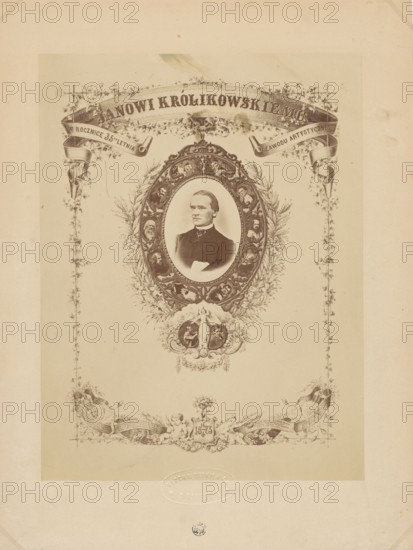 To Jan Królikowski on the 35th anniversary of his artistic profession. 14/4 1873, Kloch, Ferdynand i Dutkiewicz, Melecjusz photographic studio ; 1866-1874 author, Gerson, Wojciech 1831-1901 draughtsman co-author, Królikowski, Jan Walery 1820-1886, male portraits, Królikowski, Jan Walery 1820-1886 - iconography, portraits, actors, theatre artist, anniversaries, photographic tableau, theatre costumes, print glued with the entire surface onto cardboard, 1873, Warsaw, photography, photographic tableau, reproduction of a work of art, photographic print: height 25.1 cm, width 19.0 cm; cardboard: height 32.9 cm, width 24.7 cm, A sepia-toned ornate portrait sheet with a central oval frame containing a photographic bust of a man wearing a dark suit and a high collar, surrounded by an intricately decorated wreath-like border with small portrait medallions and floral motifs; decorative ribbon banners and vine-like embellishments extend along the top and sides, and a decorative cartouche with clas...