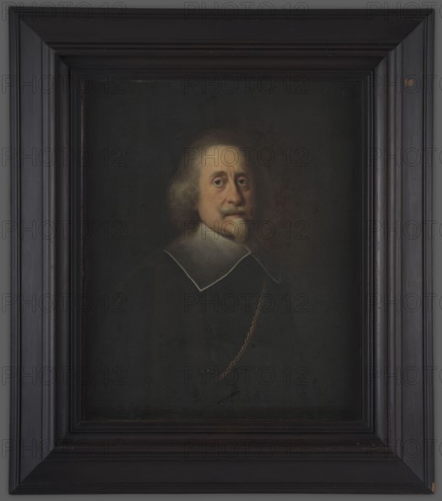 Man with a white Spanish beard, unknown painter, 1640–1660, portrait, height 79.0 cm, width 64.6 cm., A framed oil portrait of a man shown from the chest up against a dark background, with a somber color palette of black, dark gray, brown, beige, cream, and muted gold; the man has light grayish-brown hair and a short beard and mustache, a pale face with a neutral expression and visible eyes looking forward, and he wears a dark garment with a white collar outlined in a thin light line and a thin gold chain draped across his chest; the painting is set within a wide, dark wooden frame with layered molding in shades of black and very dark brown.