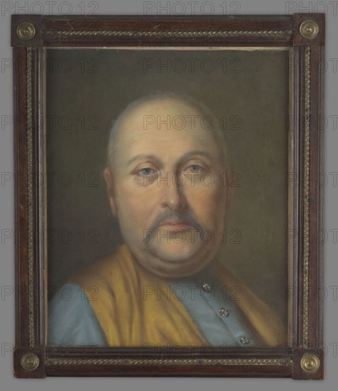 Karol Stanislaw Radziwill 1734–1790, in his youth, unknown author. Bust turned slightly to the right, head and gaze straight ahead. Blue eyes, remnants of hair—grey, ash-grey mustache. Dressed in a blue zupan and a yellow vest. Olive background. 18th century, portrait, height 38.0 cm, width 31.0 cm., A framed painted portrait of an older man shown from the chest up, with a round face, light skin tones, a receding hairline, and a mustache; his expression is neutral and his eyes look forward. He wears a garment with a muted blue section and a draped yellow-brown cloth over one shoulder, and there are a few metallic-looking buttons on the blue fabric. The background is a dark, muted brown-green. The painting is enclosed in a rectangular wooden frame with carved rope-like trim and circular brass decorative elements at the corners; the frame shows dark brown and gold tones.